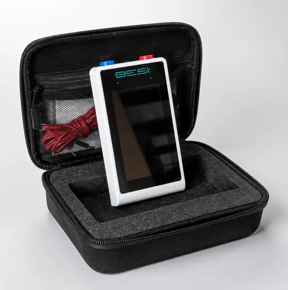 The device standing in its open travelling case, a red cable coiled beside it
