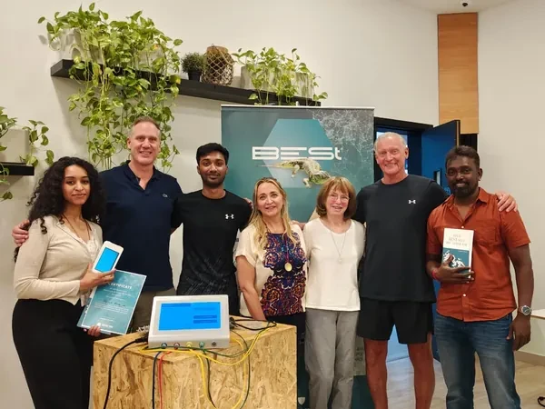 Seven people at a B-E-St training day, a device on a bench in front of them and the company's roll-up banner behind